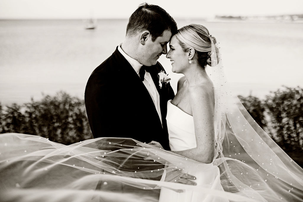 Bride and groom on the water at their Woods Hole Golf Club wedding with veil blowing in the wind