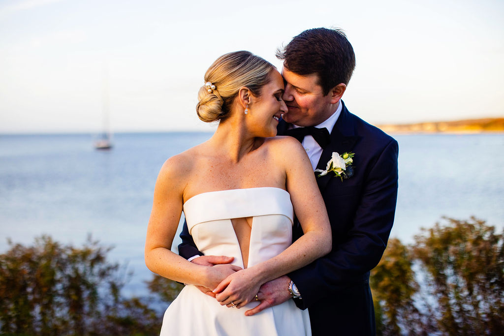 Bride and groom snuggle on the water at their Woods Hole Golf Club wedding 