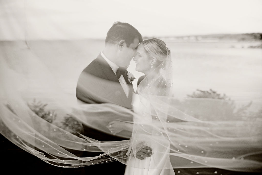 Bride and groom on the water at their Woods Hole Golf Club wedding with veil blowing in the wind