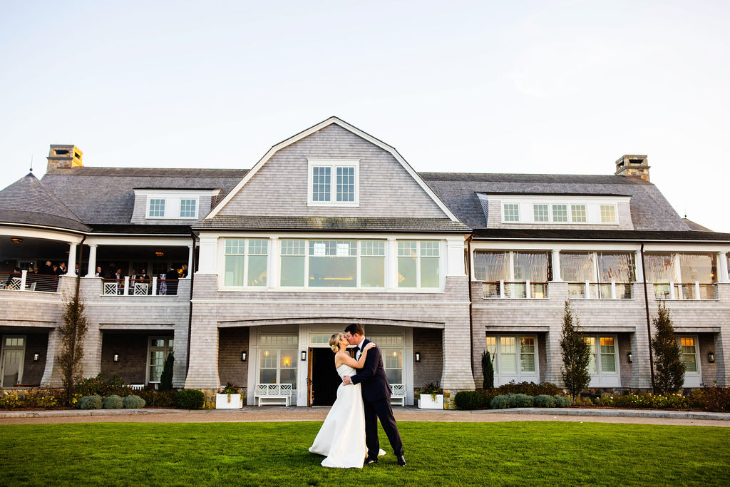 Bride and groom kiss in front of Woods Hole Golf Club