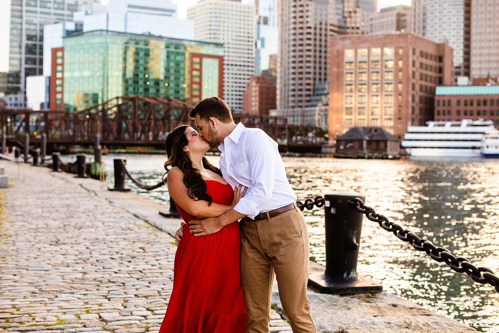 Couple kisses on the water in Boston at the seaport for their engagement photos