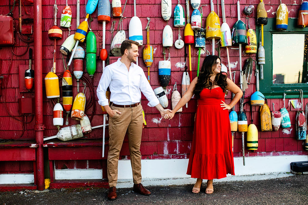 Couple stands in front of art installation called Buoys in Boston at the seaport for their engagement photos
