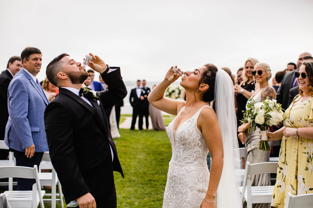 Bride and groom take a shot at the end of the aisle after their ceremony