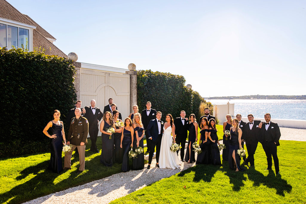 Large Wedding party poses by the ocean on the lawn at Belle Mer in Newport.