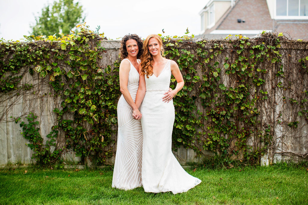 Two brides standing together outside the island house at Belle Mer