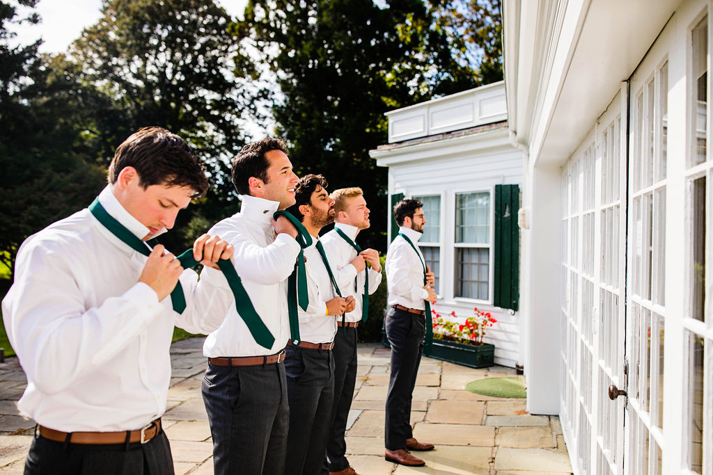 Groomsmen tying their ties before the wedding ceremony at Mount Hope Farm in Bristol