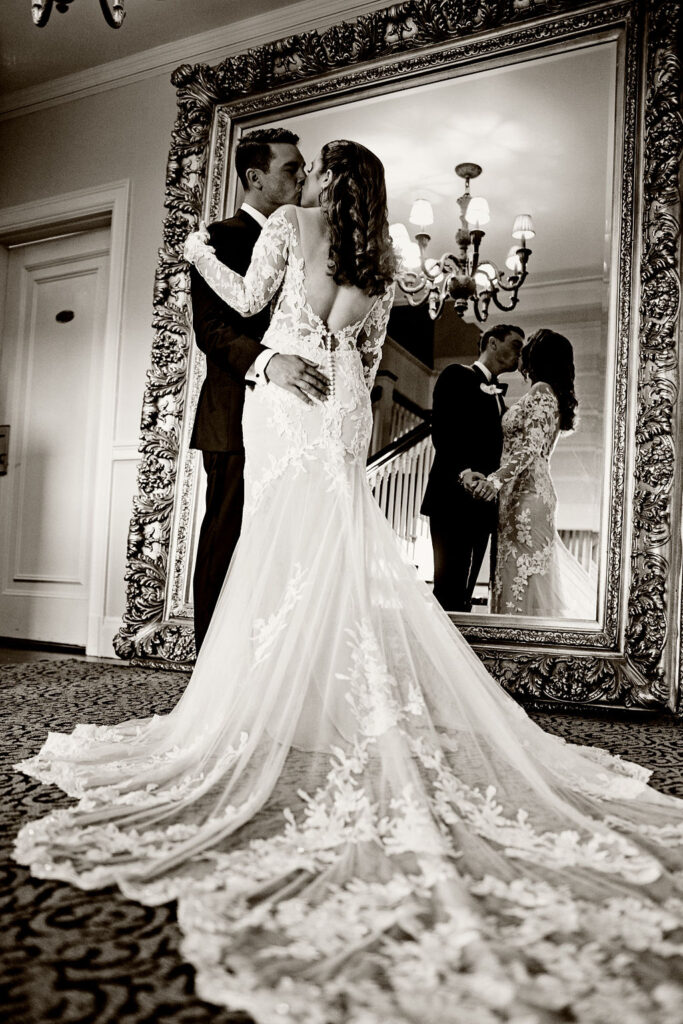 Bride and groom kissing in front of the mirror at their wedding at Oceancliff in Newport