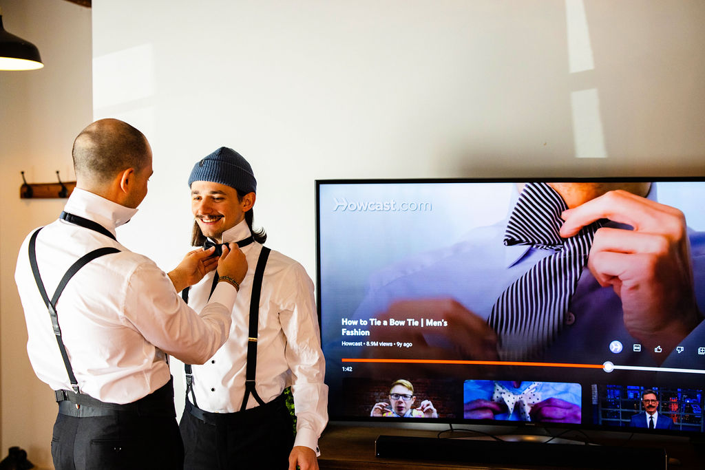 Groomsmen watching a youtube instructional video on how to tie a bow tie