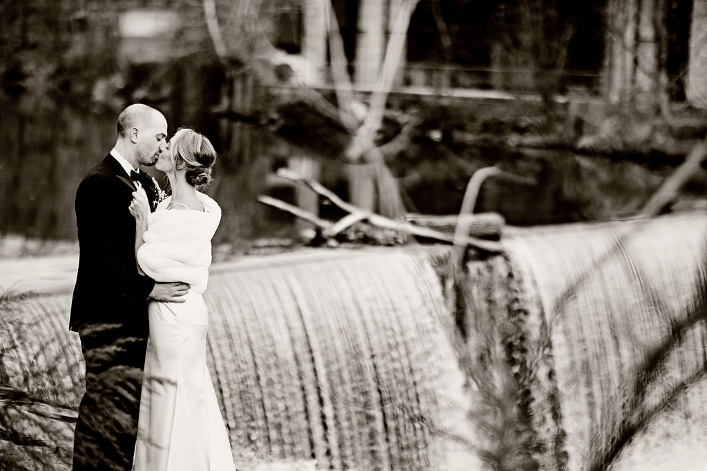 Bride and groom kissing by the waterfall next to their wedding venue, the Roundhouse, in Beacon NY