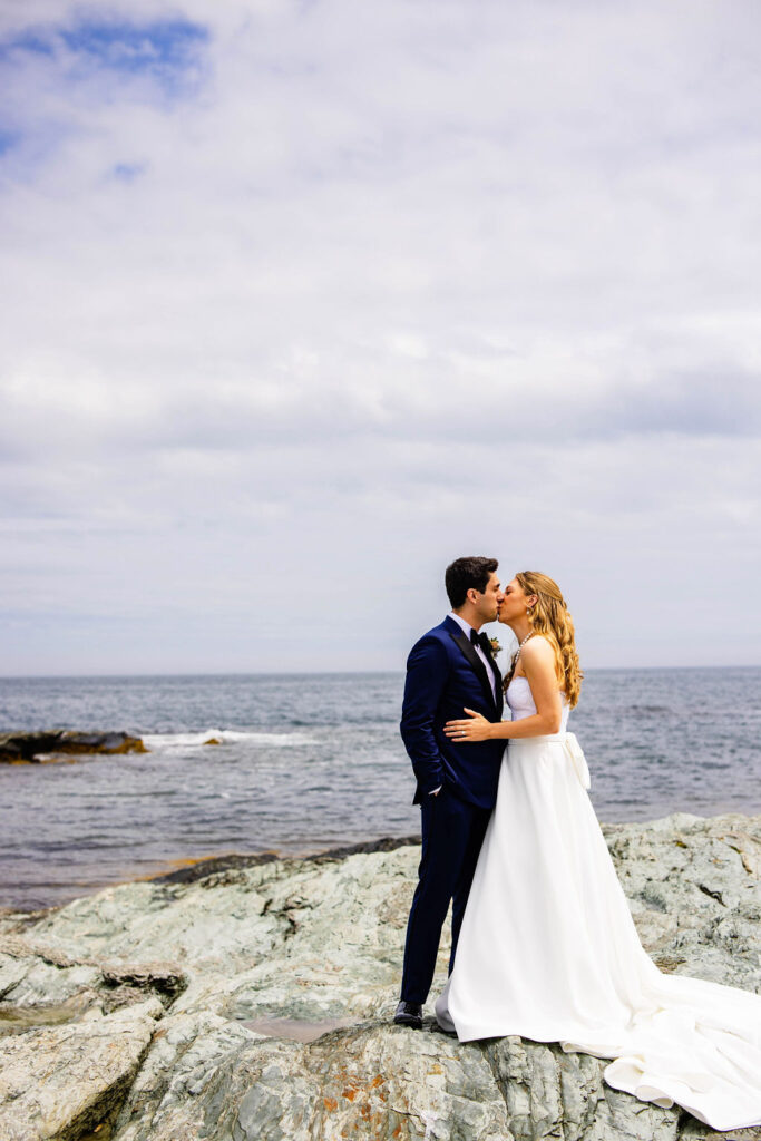 Bride and groom kissing by the water at Brenton Point in Newport, RI