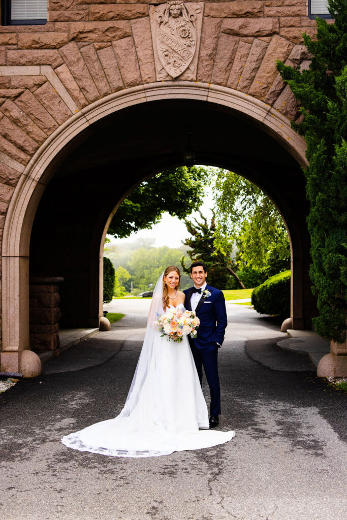 Bride and groom under arch in the front of Oceancliff in Newport, RI