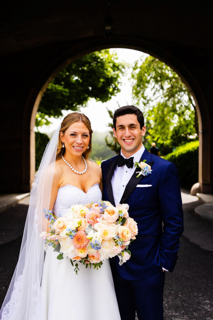 Bride and groom under arch in the front of Oceancliff in Newport, RI