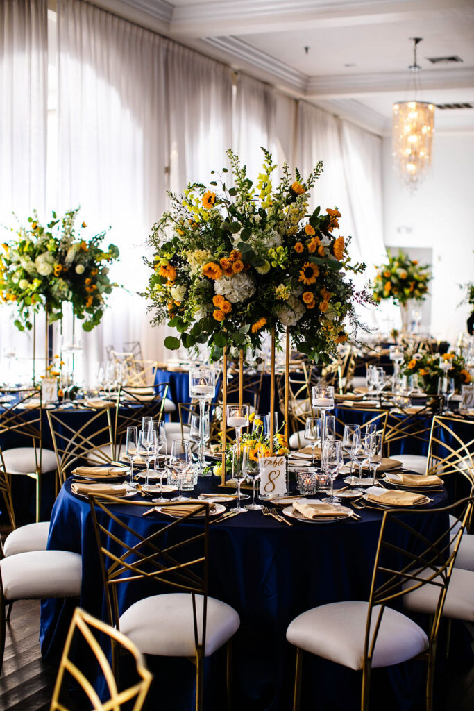 Reception space with sunflowers, navy blue linens, and gold accents at Belle Mer wedding in Newport, RI 