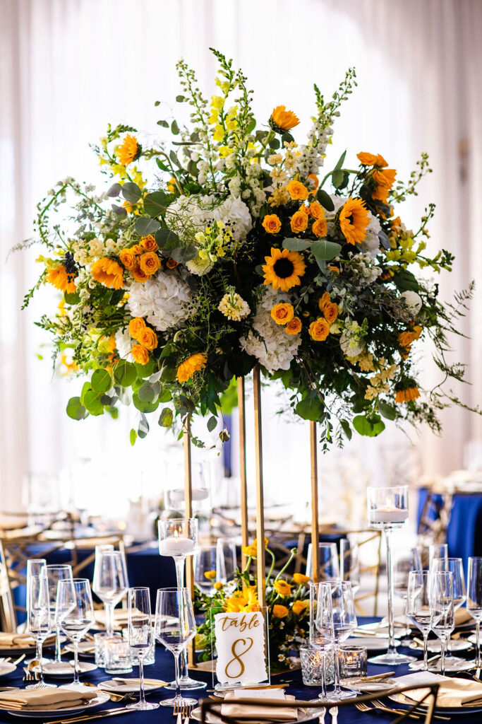 Reception space with sunflowers, navy blue linens, and gold accents at Belle Mer wedding in Newport, RI 