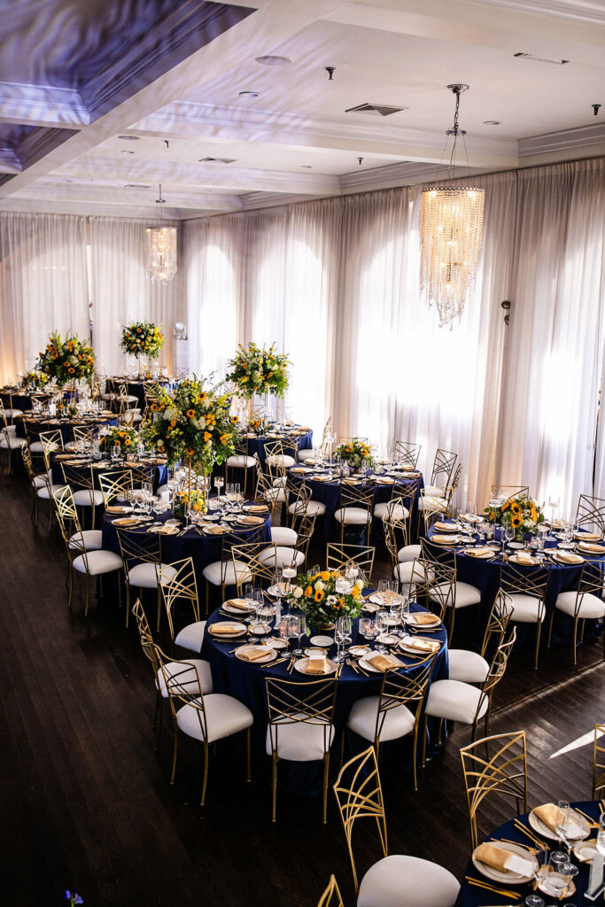 Reception space with sunflowers, navy blue linens, and gold accents at Belle Mer wedding in Newport, RI 