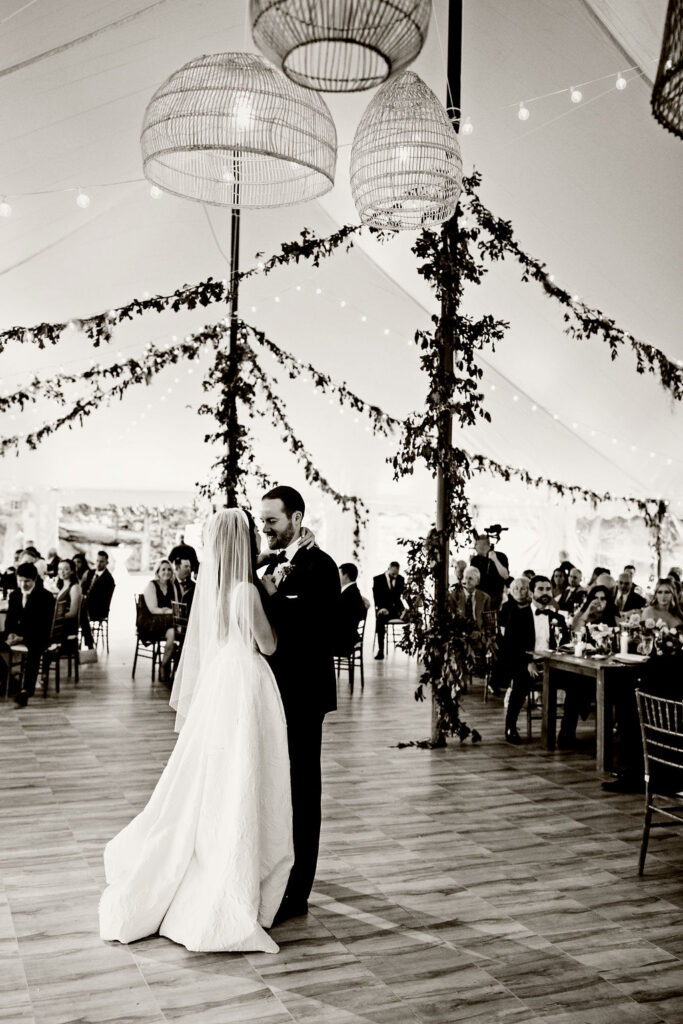 Bride and Groom having first dance in reception tent with ratan lanterns and greenery at Mount Hope Farm wedding