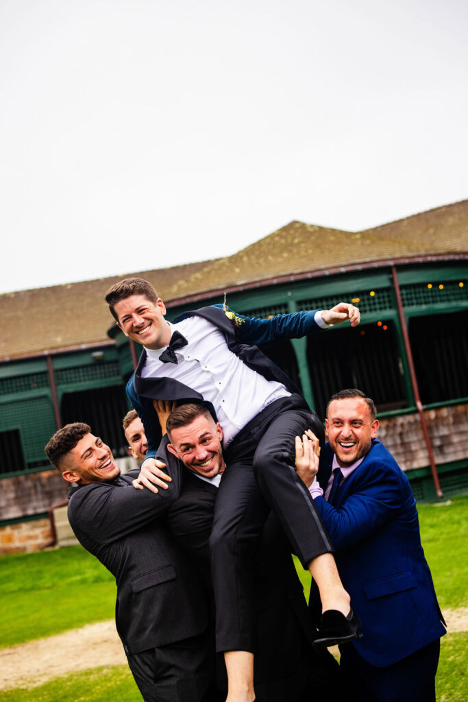 Grooms posing on the green at their Tennis Hall of Fame Wedding in Newport, Rhode Island