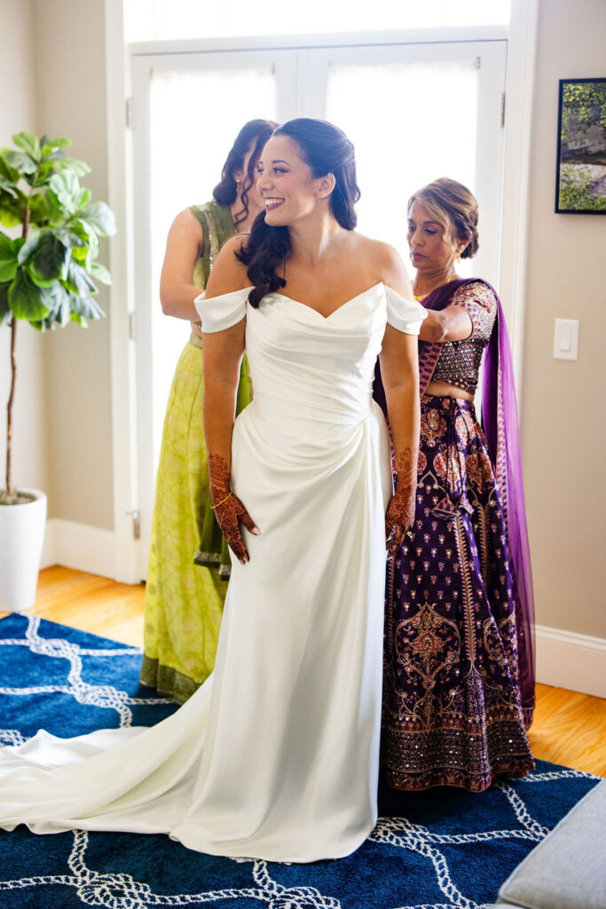 Bridesmaids helping bride get dressed for wedding 