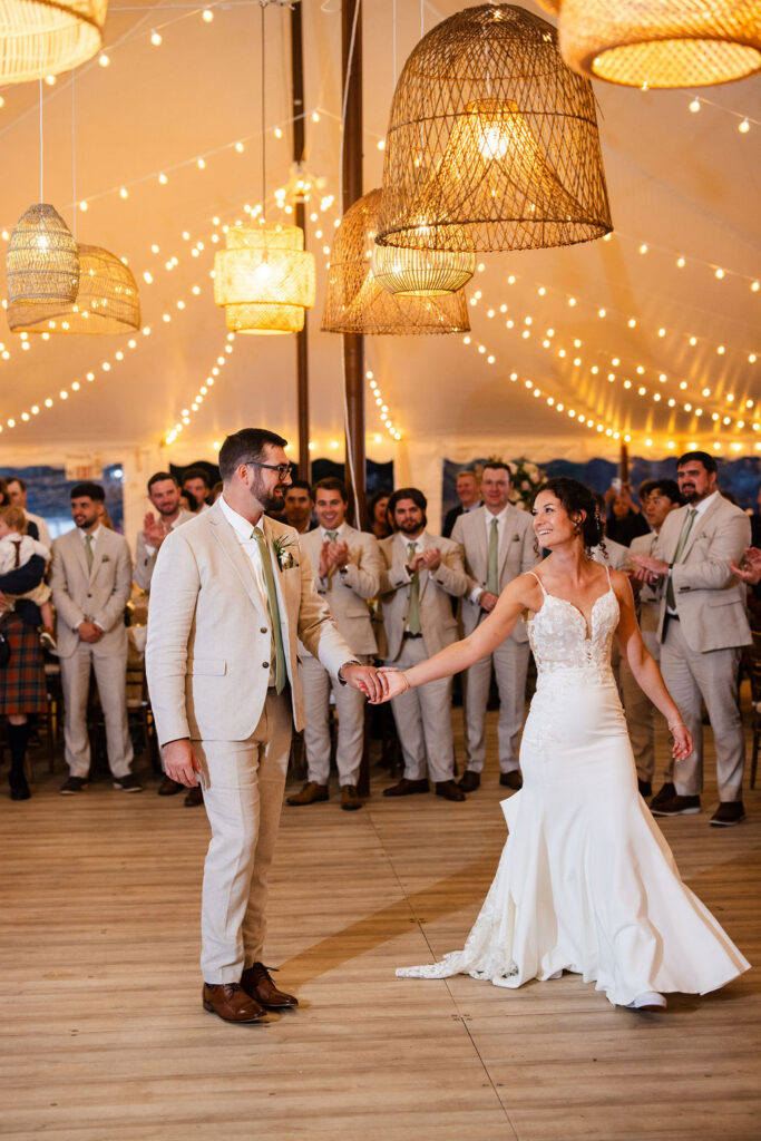 Bride and groom enter their reception under the tent at Mount Hope Farm in Bristol with edison lights and rattan lanterns