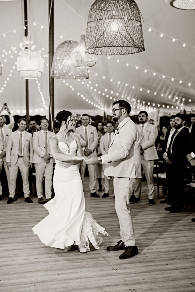 Bride and groom enter their reception under the tent at Mount Hope Farm in Bristol with edison lights and rattan lanterns