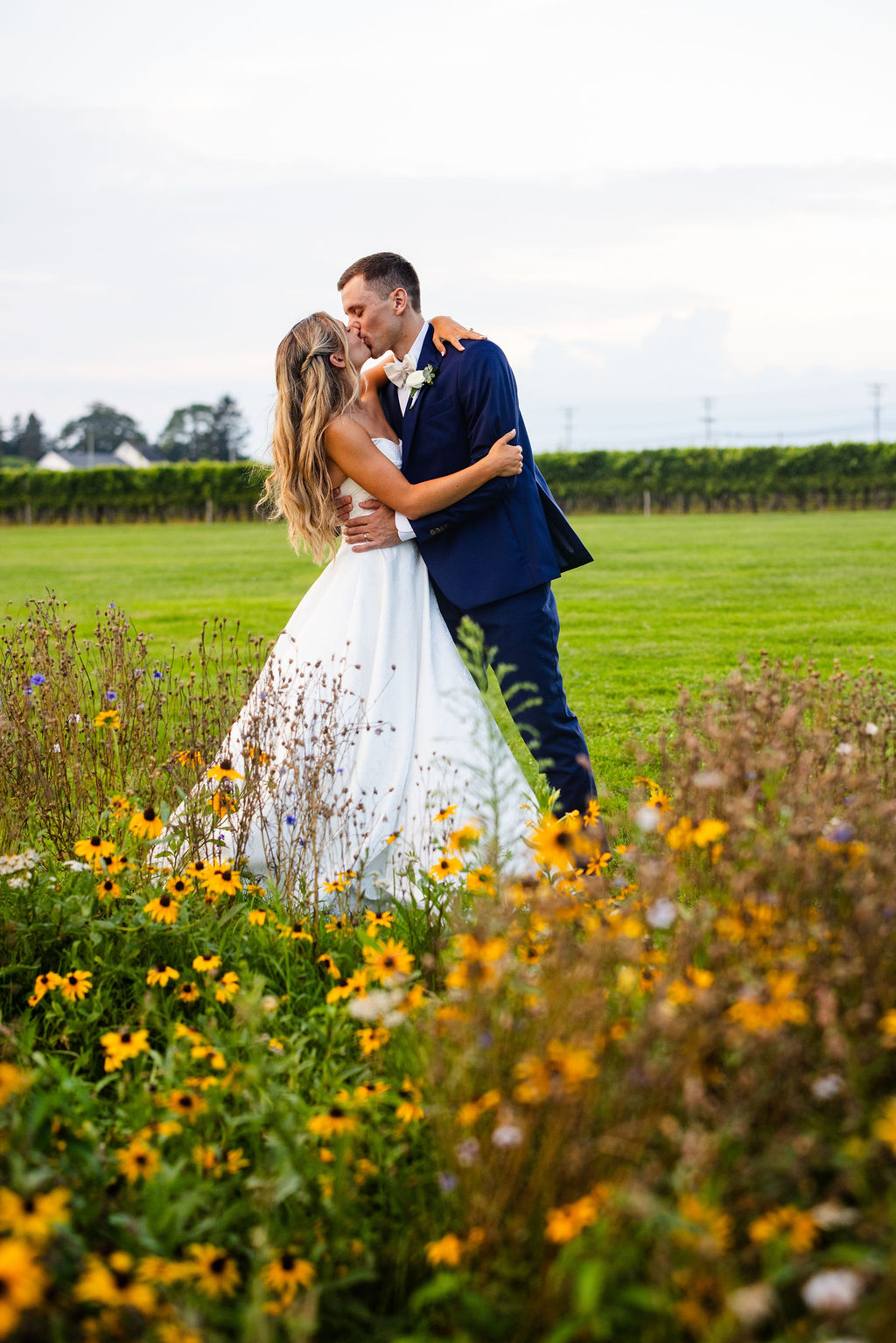 Bride and Groom kissing by the wildflowers at their wedding at Newport Vineyards in RI
